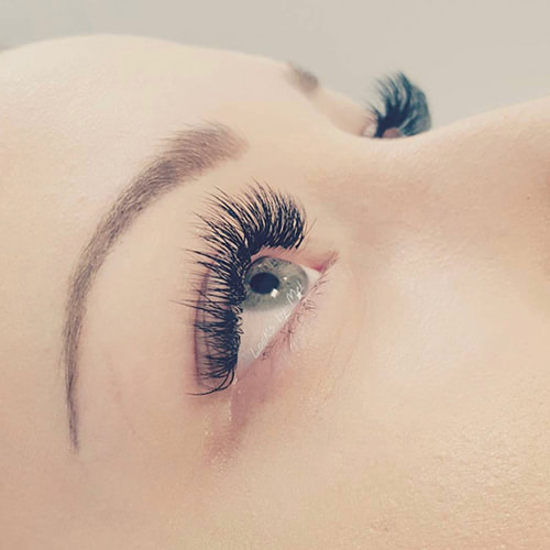 A woman's eyes and lash extensions are shown as she looks up